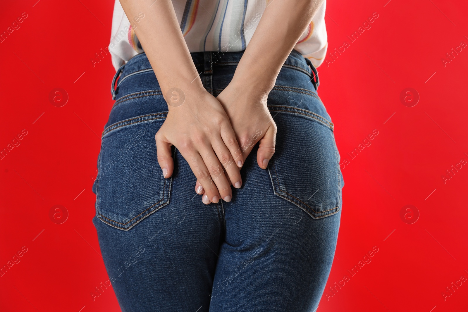 Photo of Woman suffering from hemorrhoid on red background, closeup