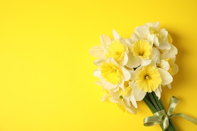 Photo of Bouquet of daffodils on color background, top view with space for text. Fresh spring flowers