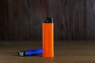 Photo of Stylish small pocket lighters on wooden table