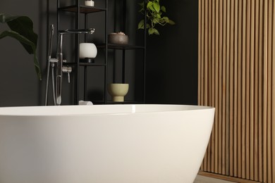 Photo of Spa day. Stylish bathroom interior with ceramic tub and houseplants