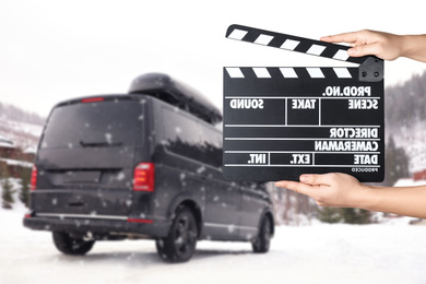 Image of Assistant  holding clapperboard and black car on snowy road, closeup. Cinema production 