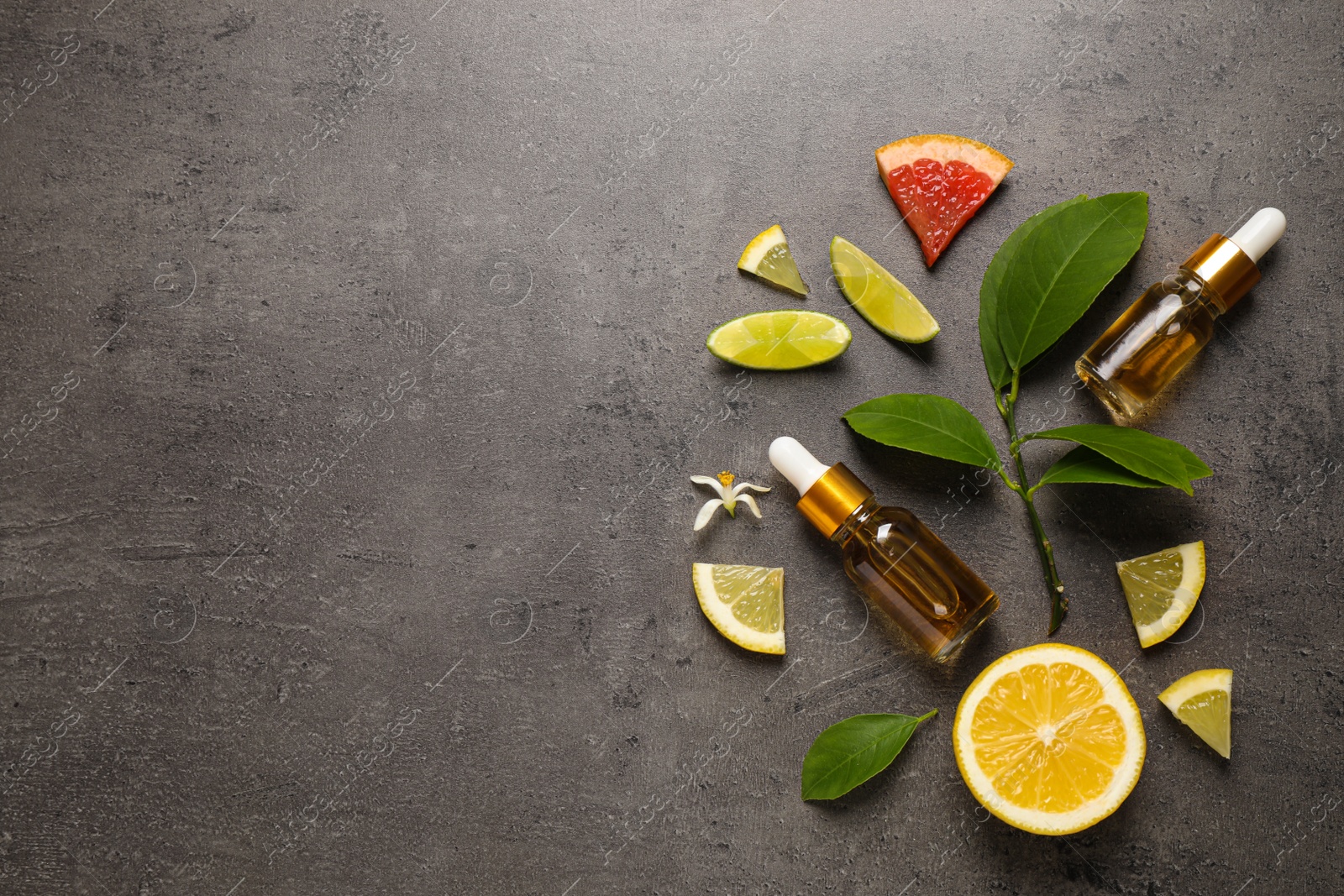 Photo of Flat lay composition with bottles of citrus essential oil on grey background. Space for text