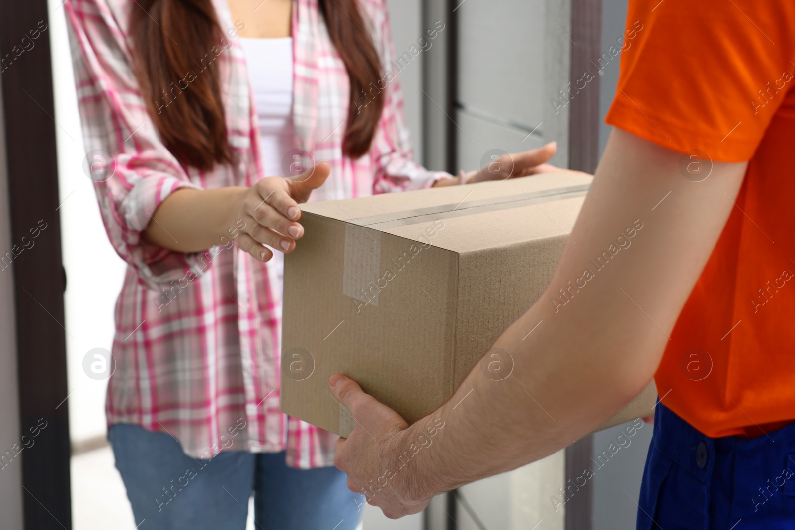 Photo of Woman receiving parcel from courier at home, closeup