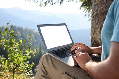 Photo of Man working on laptop outdoors surrounded by beautiful nature, closeup. Space for text