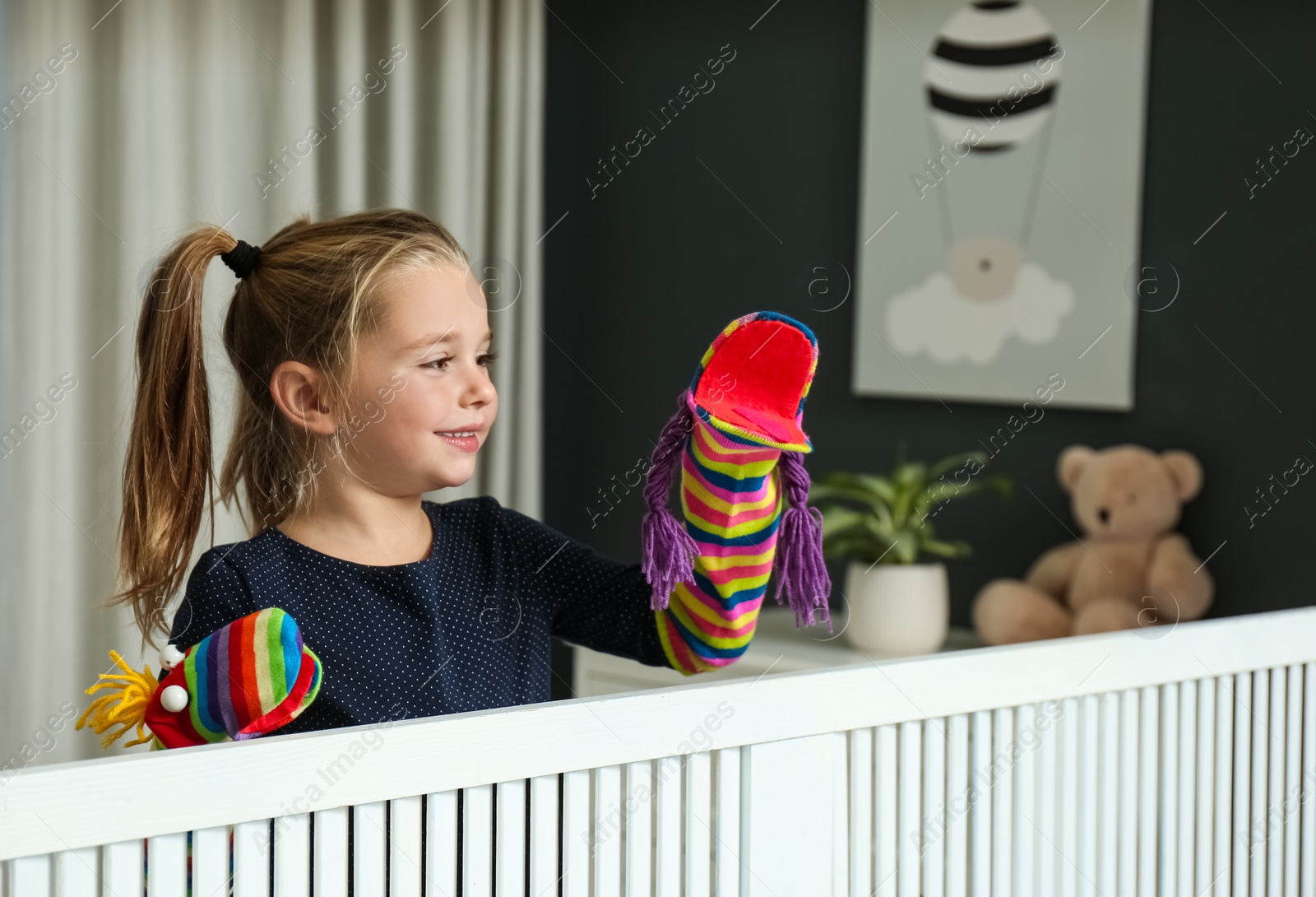 Photo of Cute little girl performing puppet show at home