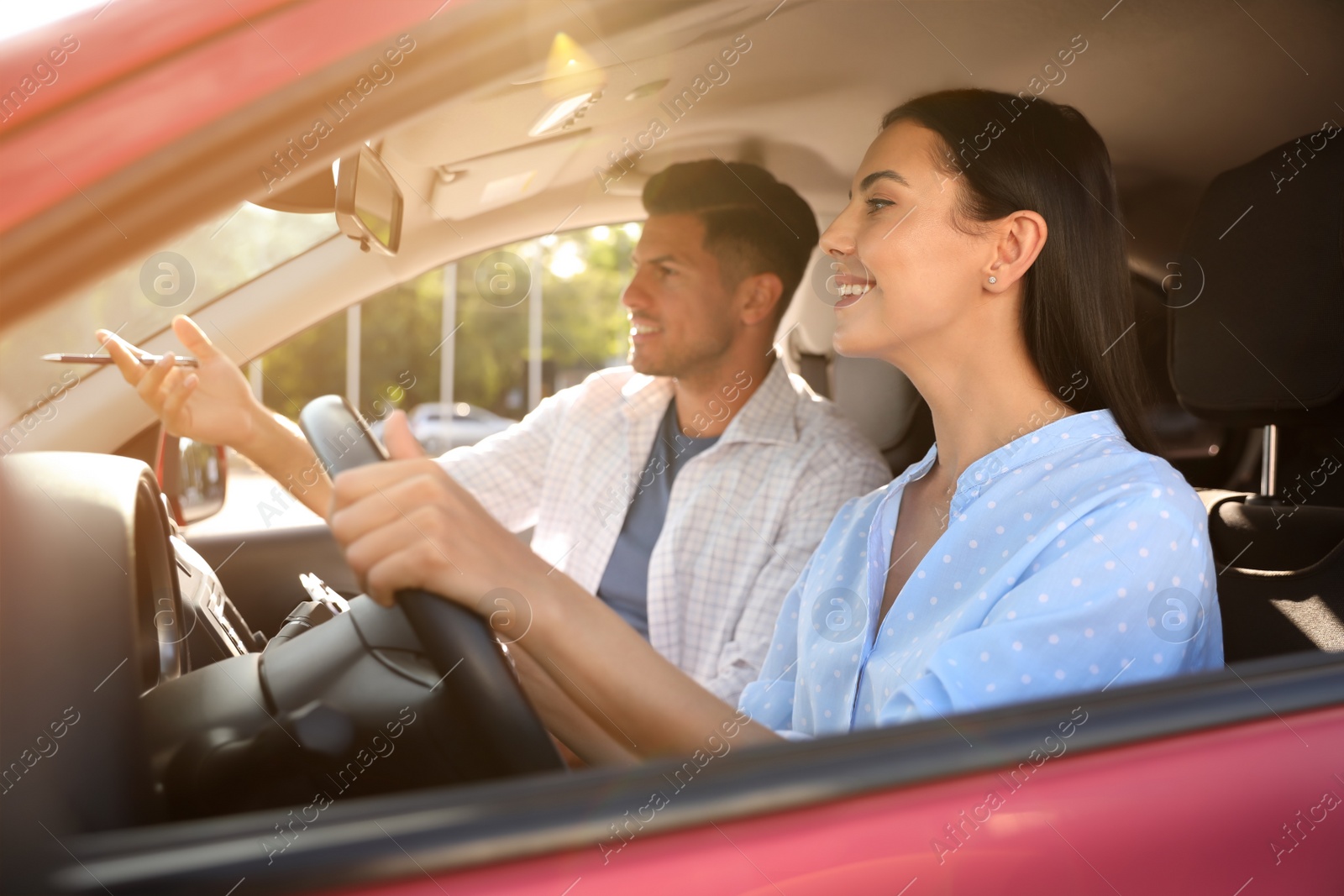 Photo of Young woman and instructor in car outdoors. Driving school