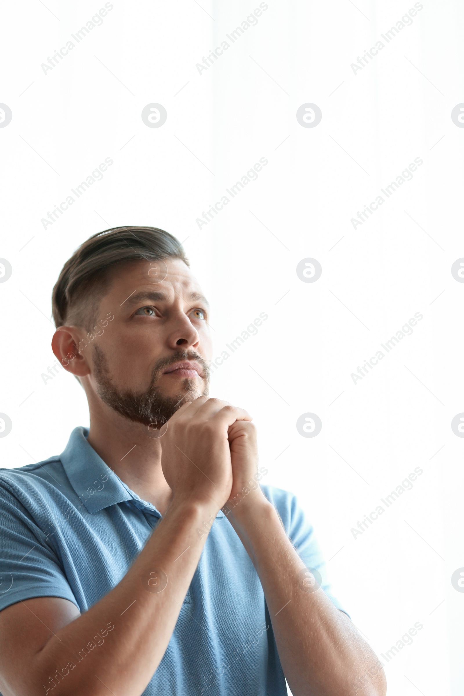 Photo of Man with hands clasped together for prayer on light background. Space for text