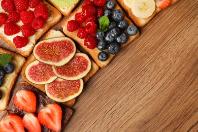 Tasty toasts with different spreads and fruits on wooden table, flat lay. Space for text