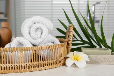 Photo of Beautiful composition with different spa products, flower and green leaves on white wooden table in bathroom, closeup