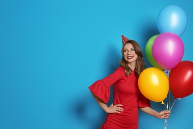 Young woman with bright balloons on color background. Birthday celebration