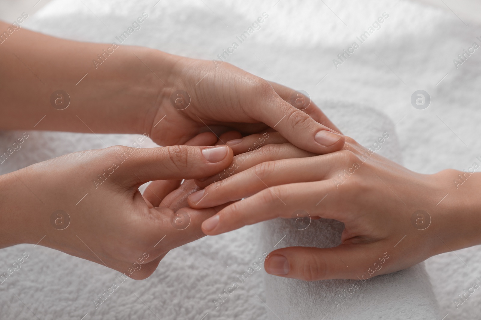 Photo of Woman receiving hand massage on soft towel, closeup