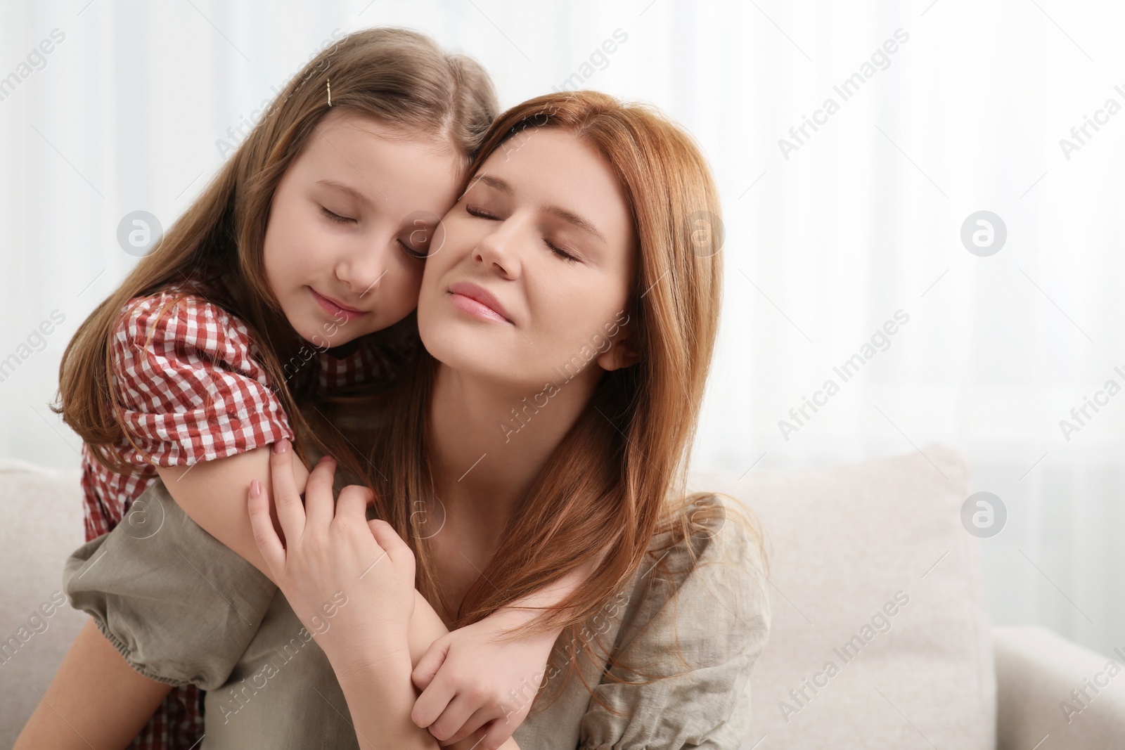 Photo of Mother and her cute daughter on sofa at home