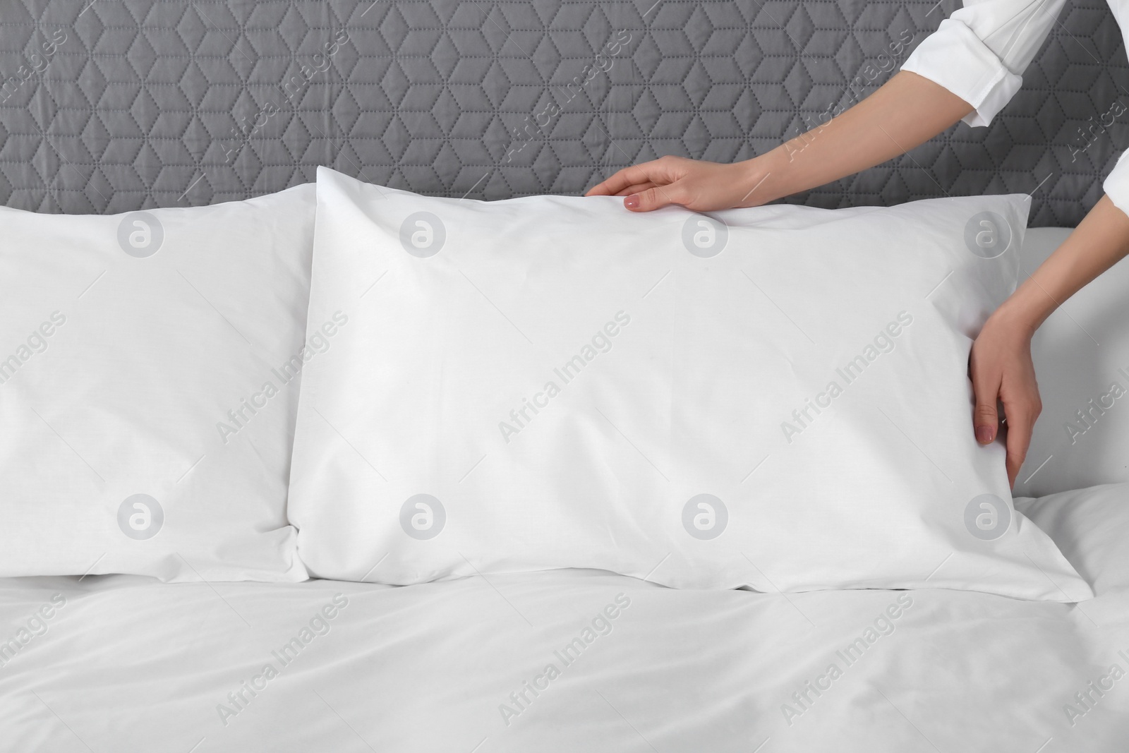 Photo of Woman fluffing soft pillow in bedroom, closeup