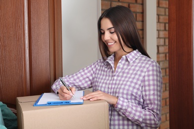 Photo of Woman receiving parcel from delivery service courier indoors