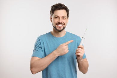 Photo of Happy man holding electric toothbrush on white background