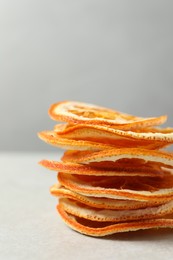 Stacked dry orange slices on white table, closeup