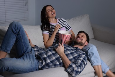 Photo of Happy couple watching comedy via TV at home in evening