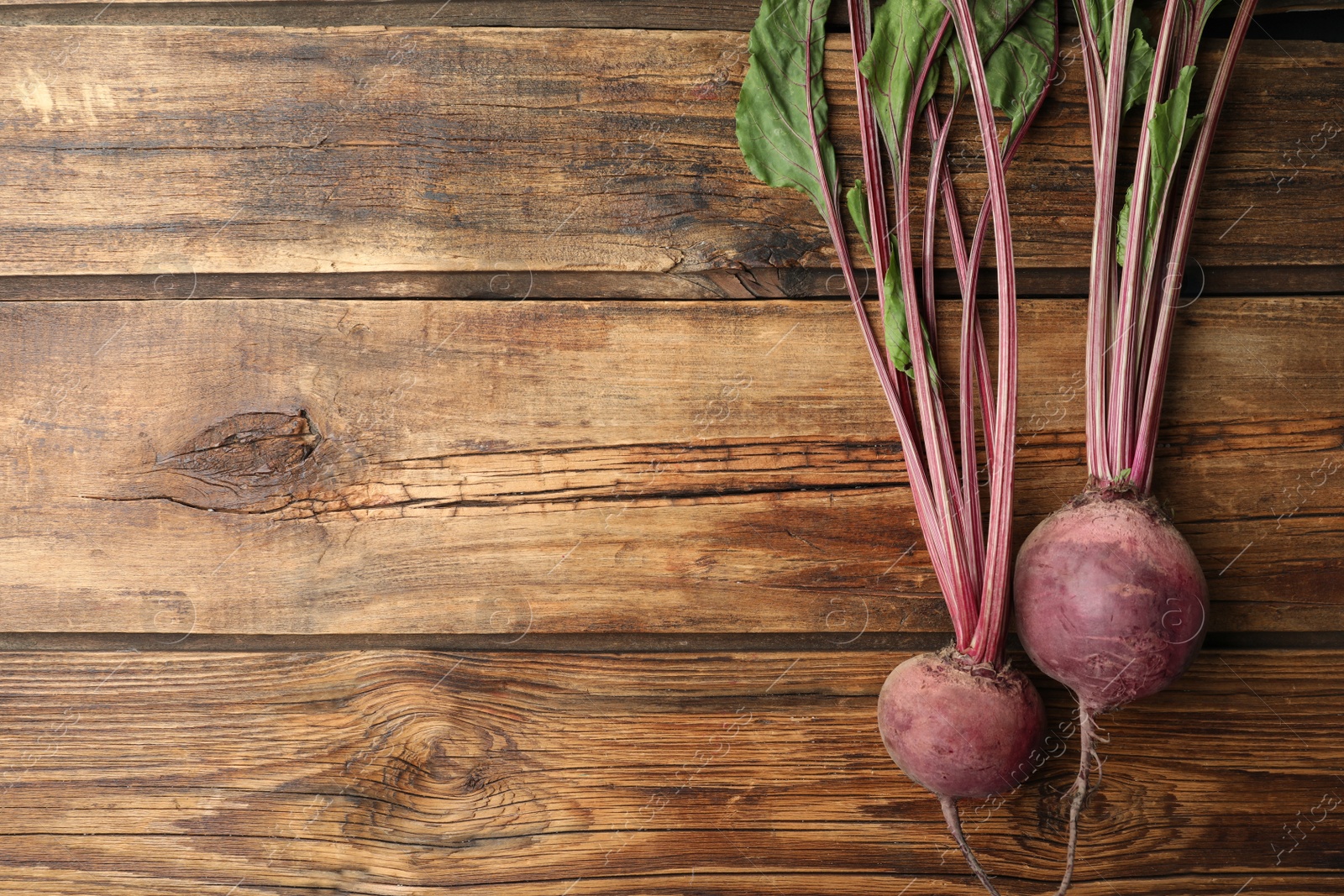 Photo of Raw ripe beets on wooden table, flat lay. Space for text