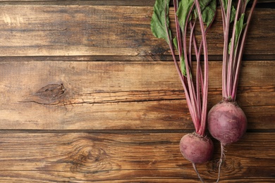 Photo of Raw ripe beets on wooden table, flat lay. Space for text