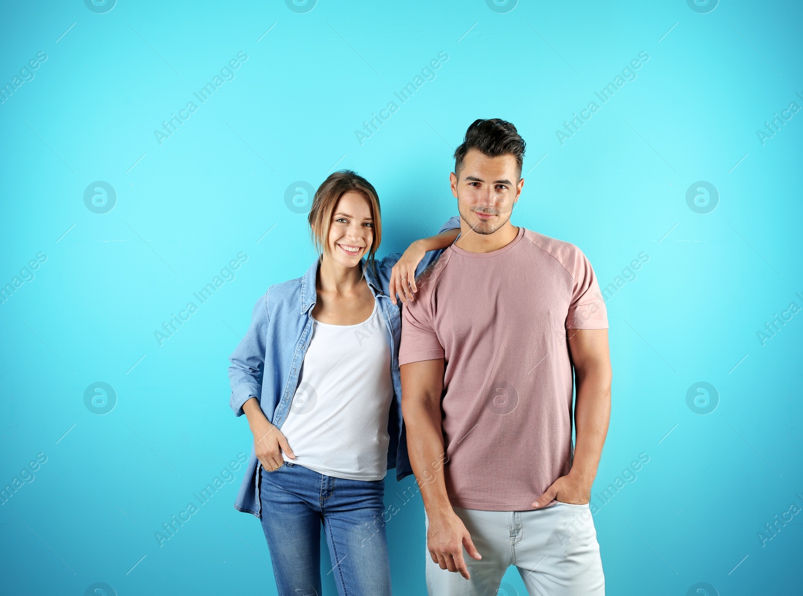 Photo of Young couple in stylish clothes on color background. T-shirts as mockup for design