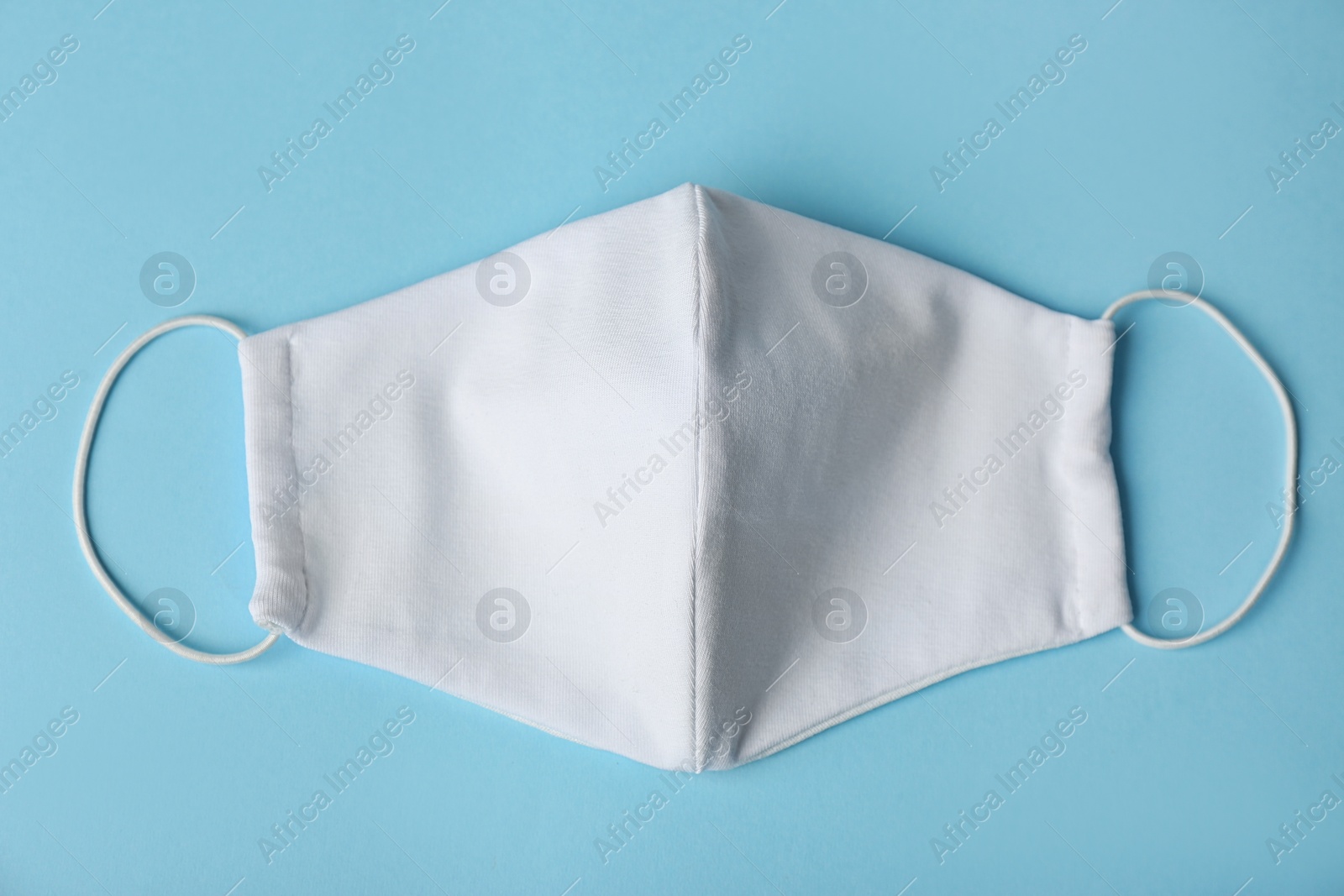 Photo of Homemade protective face mask on light blue background, top view