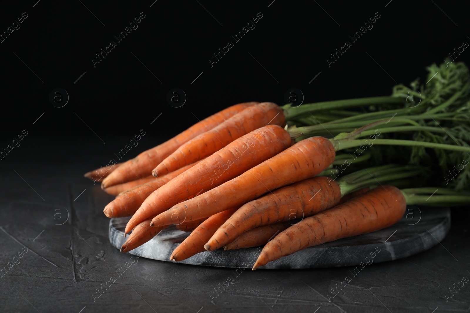 Photo of Pile of raw carrots on grey table, closeup