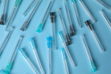 Disposable syringe needles on light blue background, flat lay