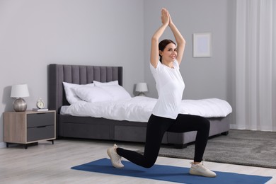 Happy woman doing morning exercise at home, space for text