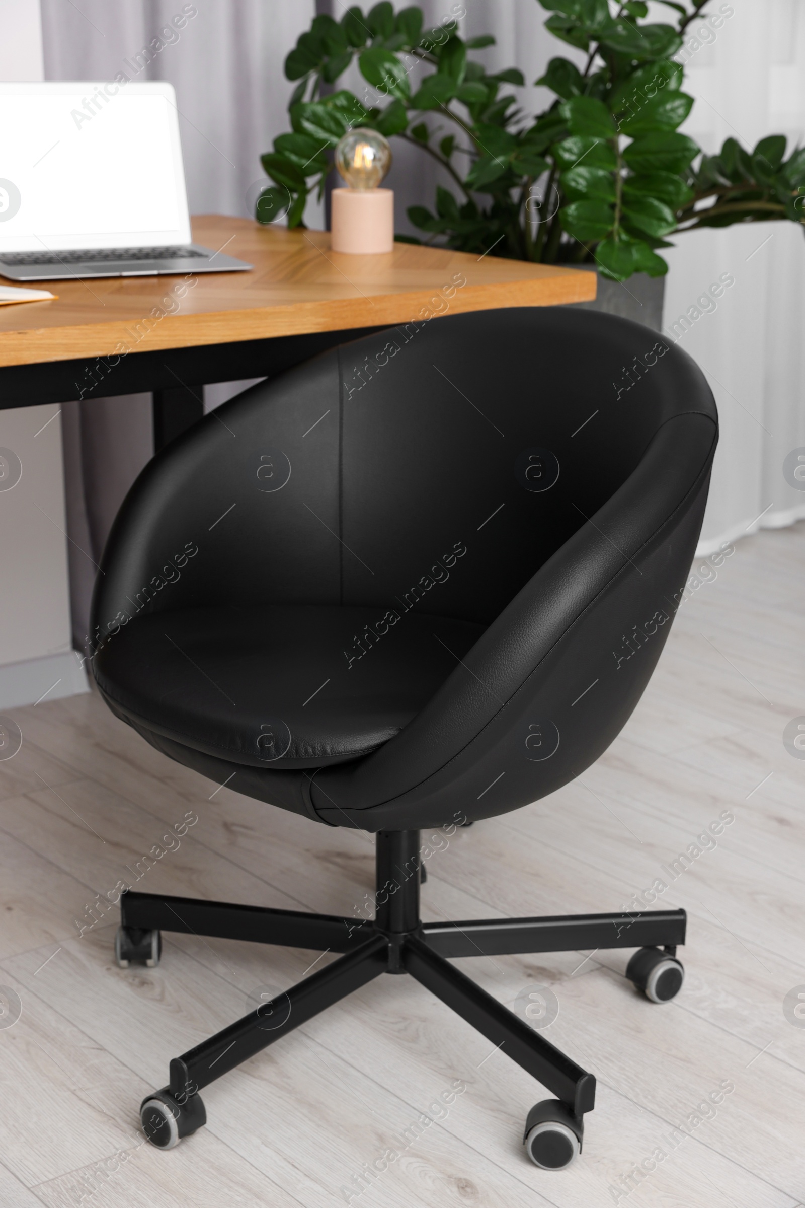 Photo of Comfortable office chair near desk in modern workplace