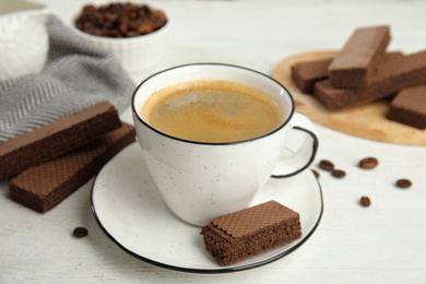 Delicious wafers and cup of coffee for breakfast on white wooden table