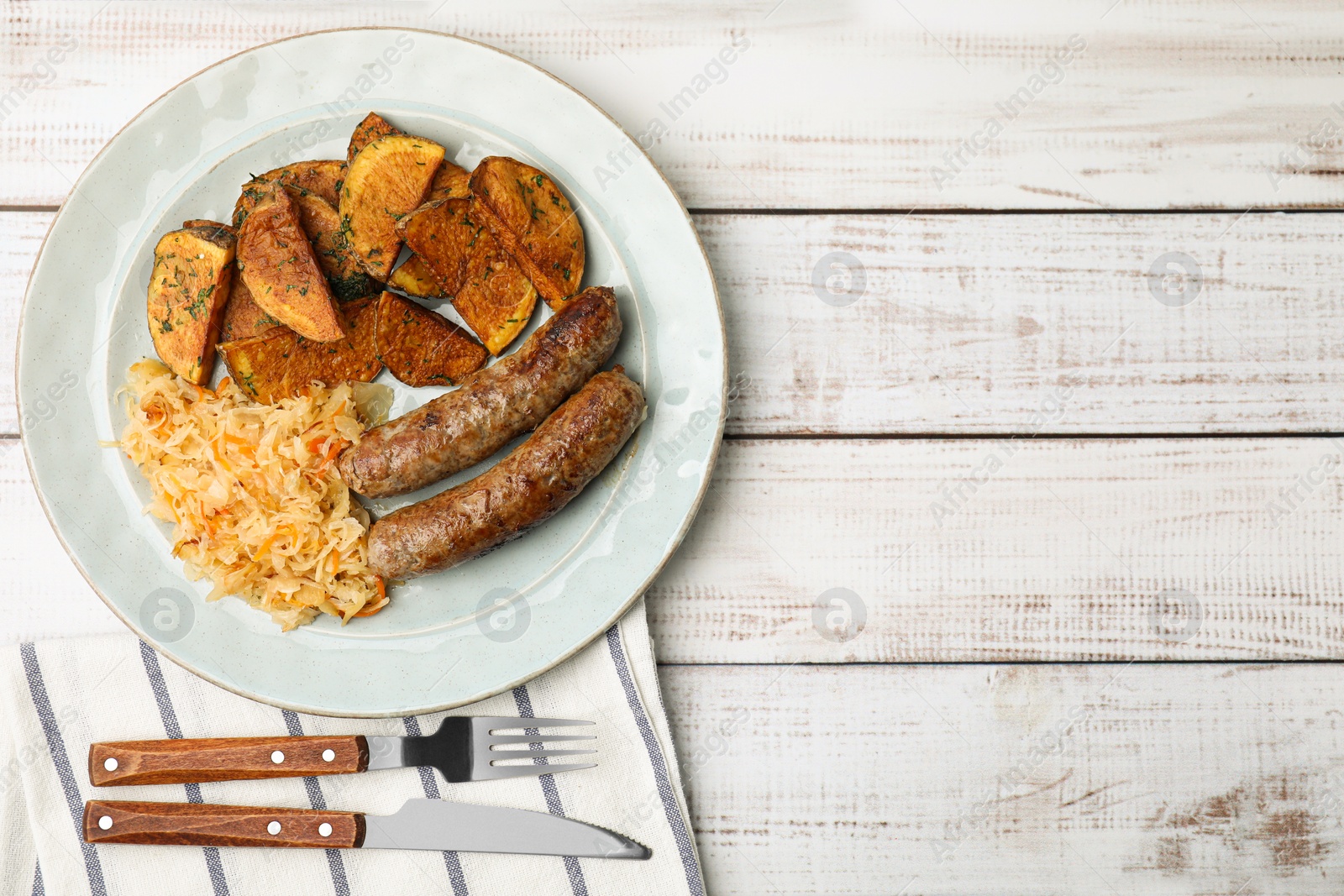 Photo of Plate with sauerkraut, sausages and potatoes on white wooden table, flat lay. Space for text