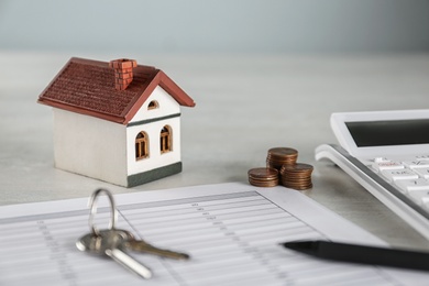 Photo of Calculator, house model, keys and documents on light table. Real estate agent's workplace