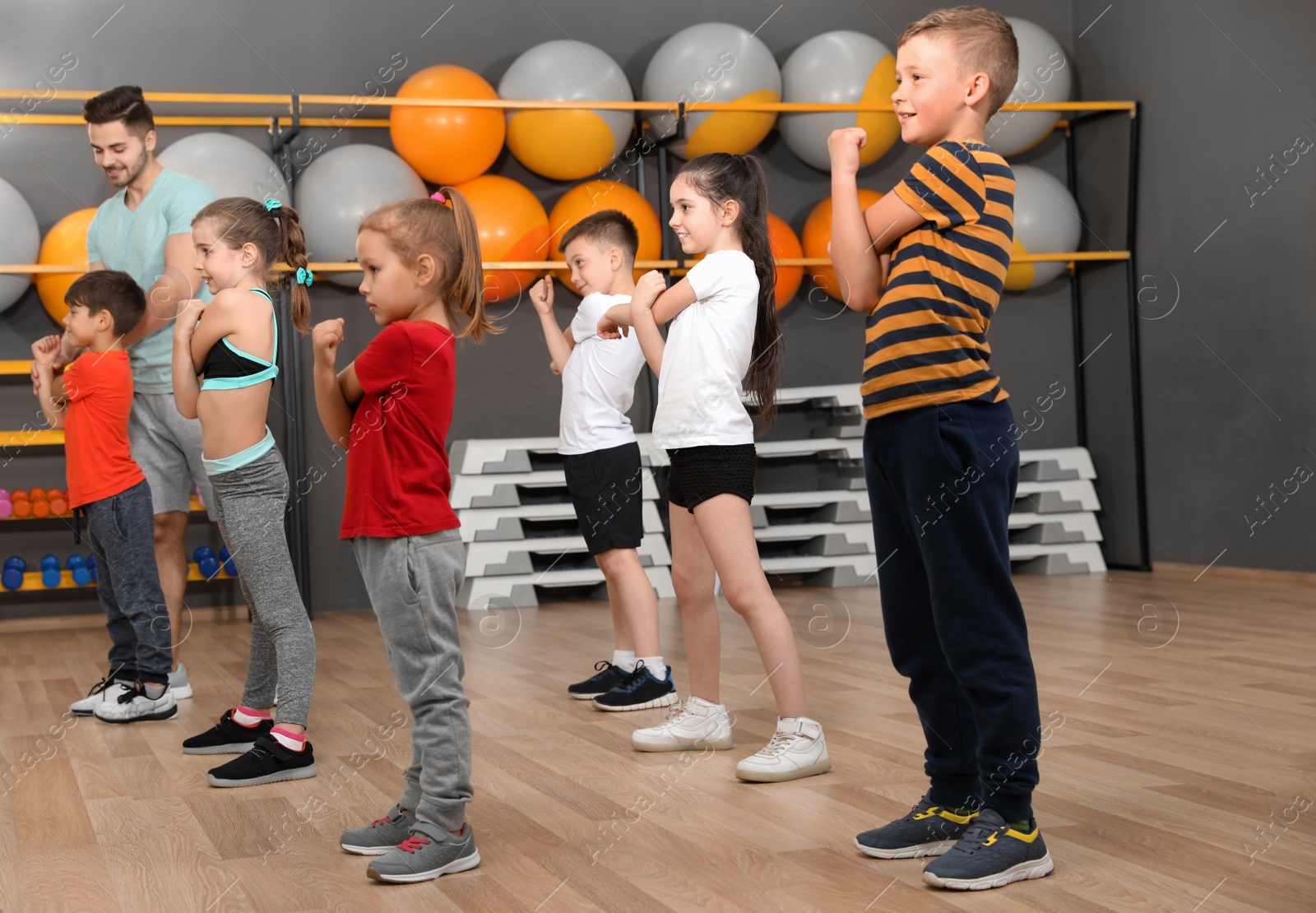 Photo of Cute little children and trainer doing physical exercise in school gym. Healthy lifestyle