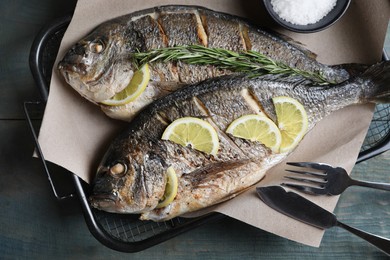 Photo of Delicious baked fish served on wooden rustic table, top view. Seafood