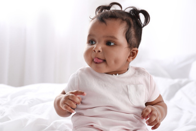 Photo of Cute African American baby on bed at home