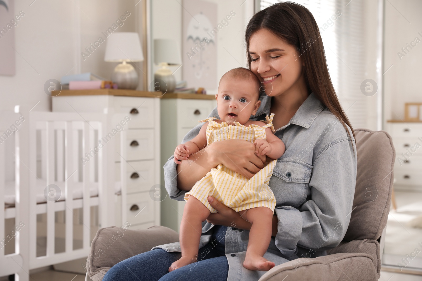 Photo of Happy young mother with her cute baby in armchair at home