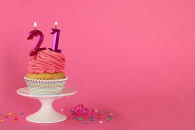 Photo of Delicious cupcake with number shaped candles on pink background, space for text. Coming of age party - 21th birthday