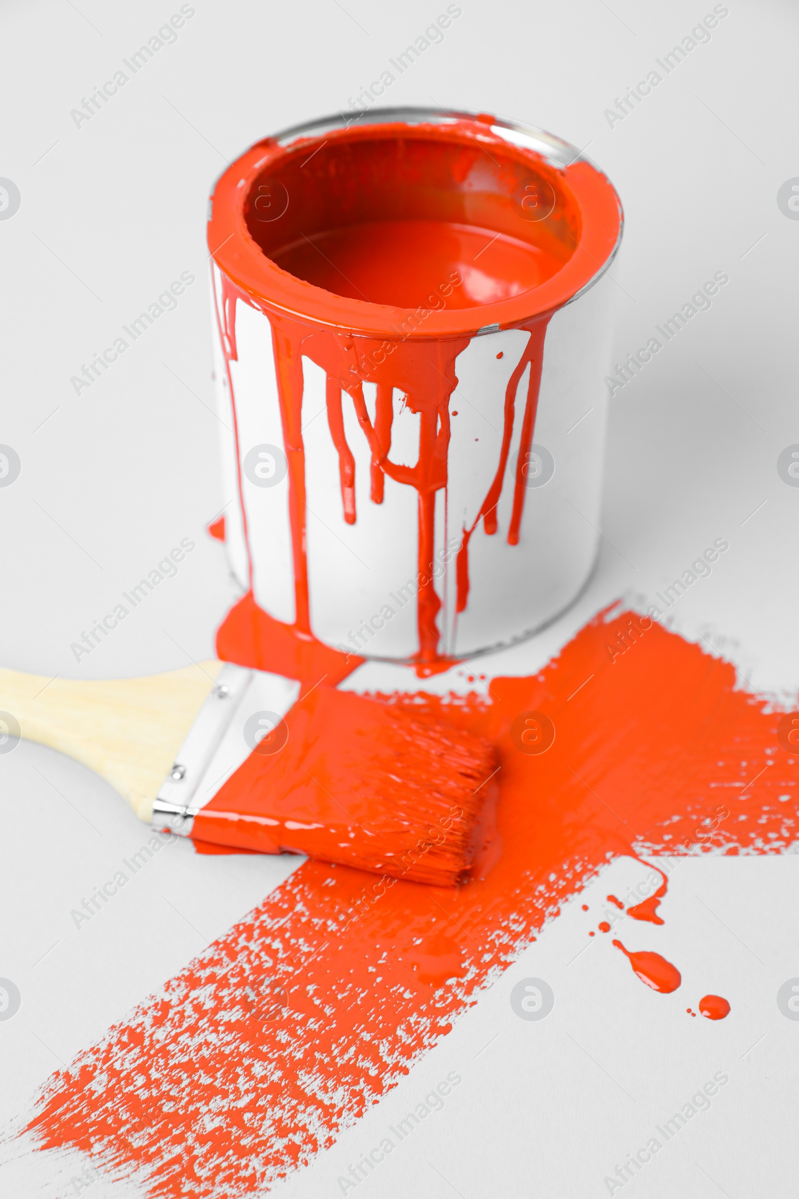 Photo of Can of orange paint and brush on white background