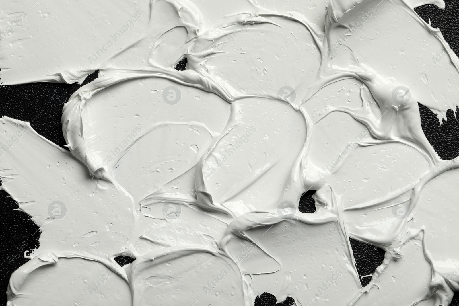 Photo of Strokes of white oil paint on black canvas, closeup