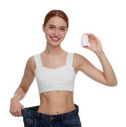 Photo of Slim woman in big jeans with bottle of pills on white background. Weight loss