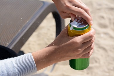 Photo of Woman opening can with sparkling drink at beach, closeup