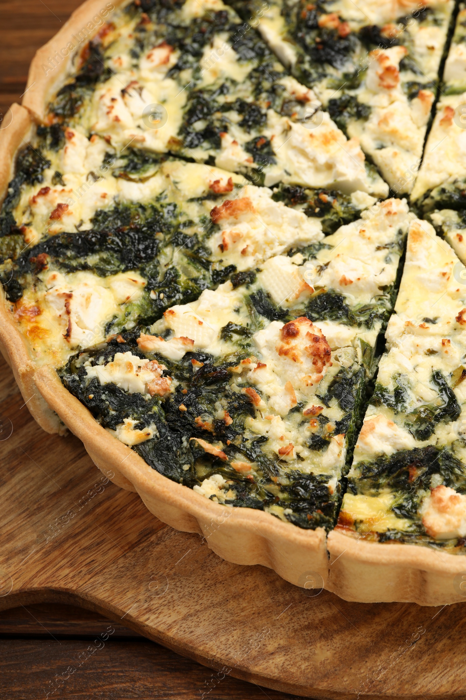 Photo of Delicious homemade spinach quiche on wooden board, closeup