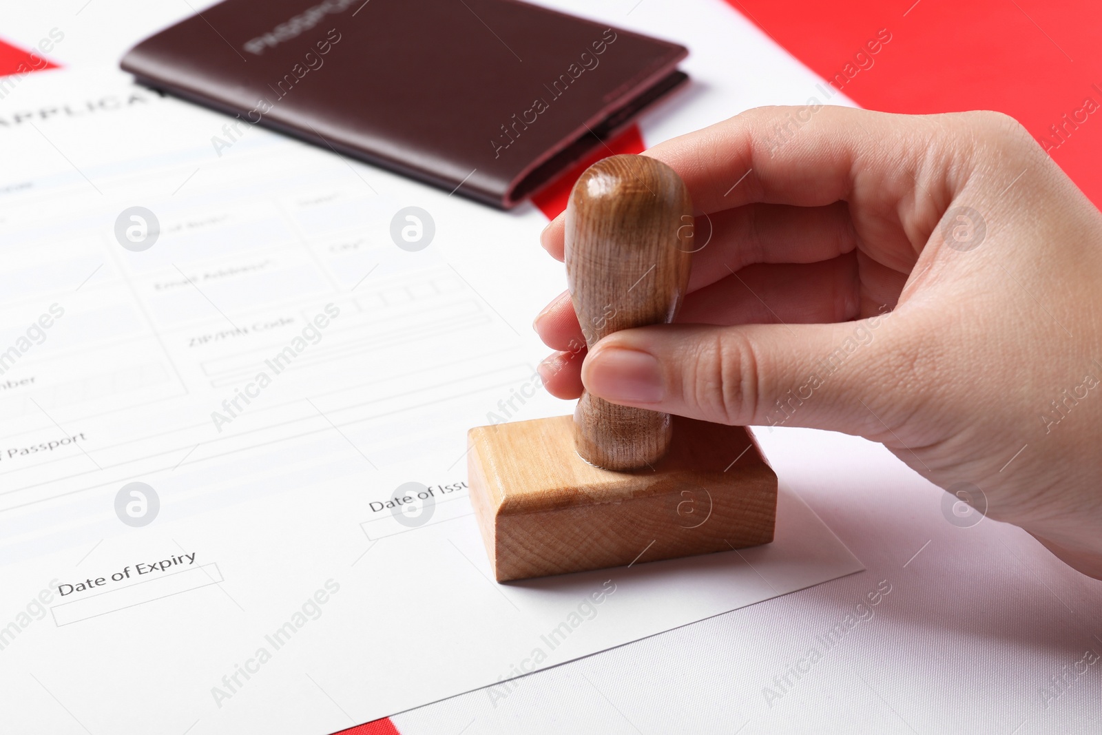 Photo of Immigration to Canada. Woman stamping visa application form on flag, closeup