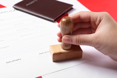 Immigration to Canada. Woman stamping visa application form on flag, closeup