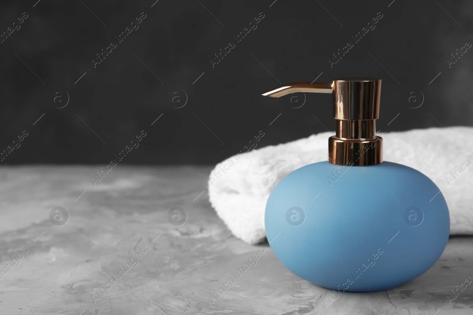 Photo of New stylish soap dispenser and towel on table. Space for text