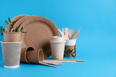 Photo of Eco disposable tableware with green twigs on light blue background. Space for text