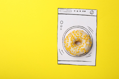 Photo of Washing machine made with donut and paper on yellow background, top view. Space for text