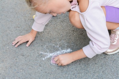 Photo of Little child drawing butterfly with chalk on asphalt, closeup