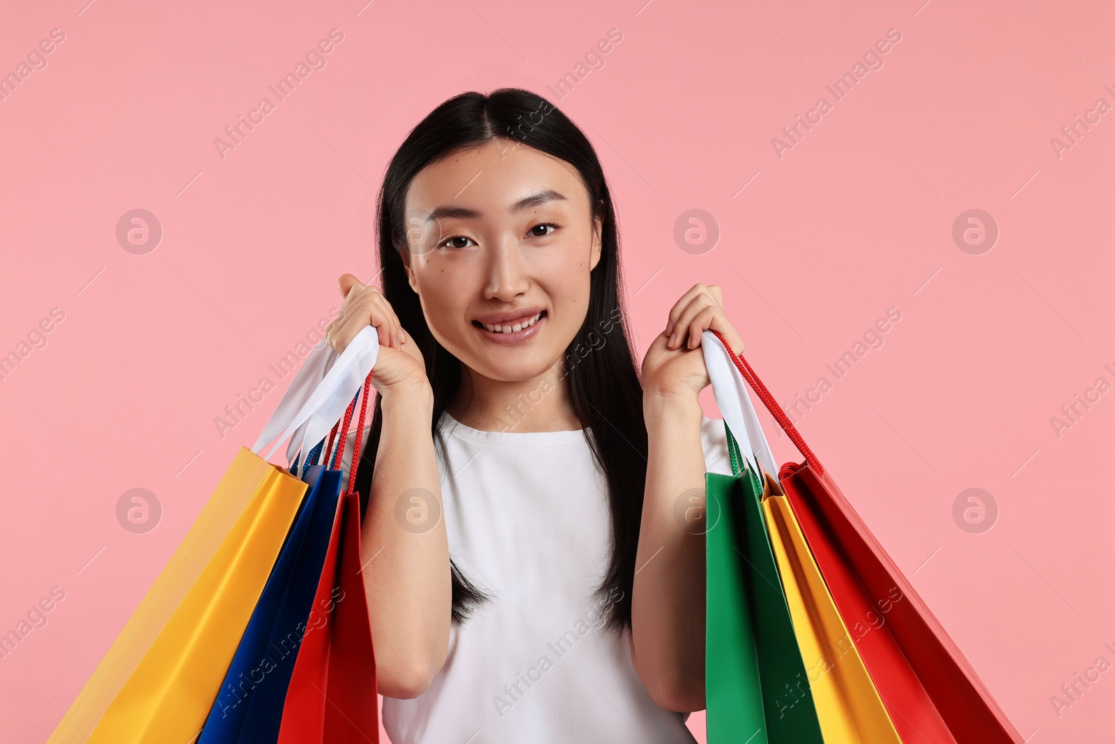 Photo of Smiling woman with shopping bags on pink background