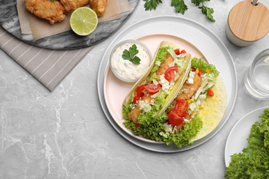 Photo of Delicious fish tacos served on grey marble table, flat lay